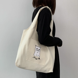 Detail of canvas tote bag featuring an external pocket with a cute cat line drawing