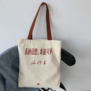 Detail of canvas tote bag featuring red Chinese calligraphy and woven brown handle straps