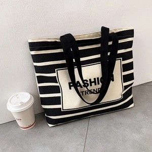 Detailed shot of striped canvas tote bag with Fashion Trend logo and sturdy handles