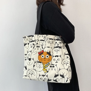 Detail of canvas tote bag with cute cartoon cat patterns and black nylon shoulder straps