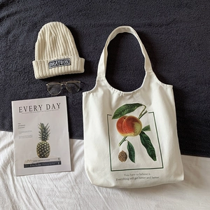 Vue à plat d'un sac cabas en toile avec bonnet en tricot et lunettes dorées