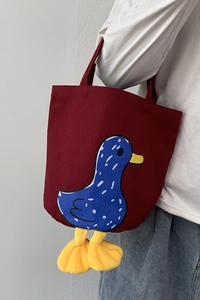 Side view of dark red canvas lunch bag with cartoon duck and 3D plush feet detail