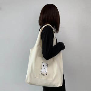 Close-up of minimalist cat illustration and front pocket on off-white canvas tote bag