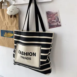 Detailed view of large black and white striped canvas tote bag with FASHION TRENDS print