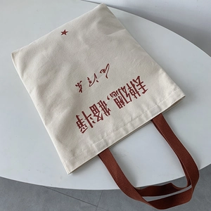 Detail of canvas tote bag featuring red star icon and printed inspirational quotes