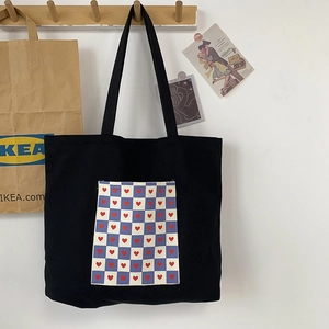 Japanese style black canvas tote bag with heart checkerboard pocket hanging on a wall