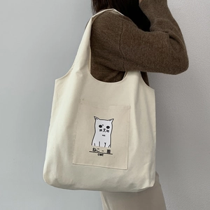 Detail of off-white canvas tote bag featuring a cute cat illustration and functional pocket