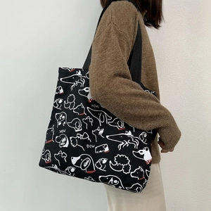 Detail of a large black canvas tote bag with cute white cartoon dog patterns and red accents