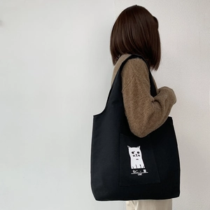 Detail of the black canvas tote bag featuring a cute white cat print and Japanese text