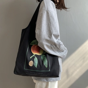 Sac fourre-tout en toile noire avec imprimé pêche et bandoulière sur un modèle