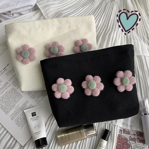 Detailed view of canvas cosmetic bags with 3D floral accents and elegant gold zippers