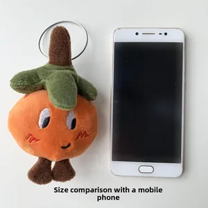 Plush orange fruit charm size comparison with a mobile phone on a white background