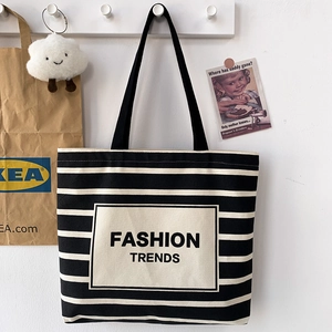 Detail of black and white striped canvas tote with FASHION TRENDS label and shoulder strap