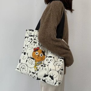 Detail of a large canvas tote bag with cute cat illustrations and black nylon straps