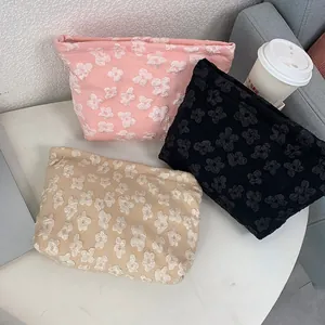 Detailed close-up of textured floral makeup bags in pink, black, and beige fabric colors