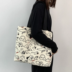 Detail view of canvas tote bag featuring artistic dog prints and black shoulder straps