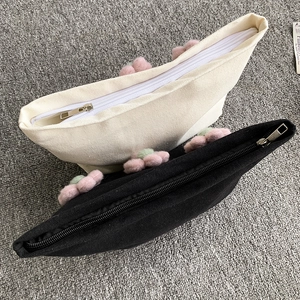 Detail of canvas makeup bags featuring 3D floral decorations and sturdy metal zippers