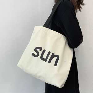 Detail of white canvas tote bag with black sun print and contrast shoulder straps
