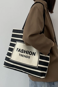 Detail of a large striped canvas tote bag featuring Fashion Trends print and wide strap