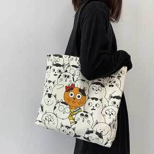 Detail shot of canvas tote bag featuring cute orange cat illustration and black straps
