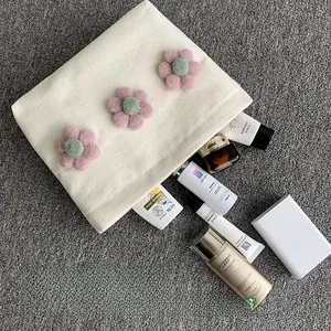 Capacity view of canvas makeup bag with 3D floral accents holding skincare bottles