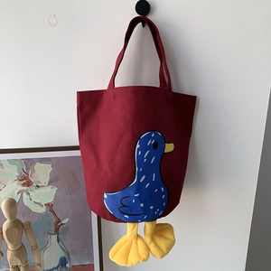 Detail of red canvas lunch bag featuring a 3D yellow plush duck feet and cartoon print