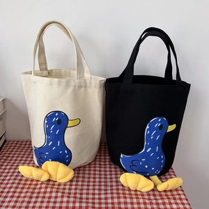 Detail of canvas lunch bags in white and black with cute 3D plush duck feet decoration