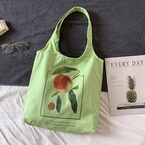 Détail de la texture d'un sac cabas en toile vert clair avec motif de pêche et texte