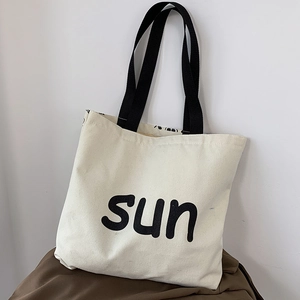 Detailed close-up of large canvas tote bag with sun print and black textile straps