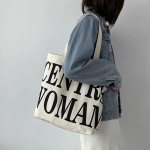 Detail of minimalist cream canvas tote bag featuring bold black CENTRE WOMAN text
