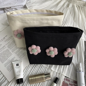 Detail of floral canvas makeup bags with zippers shown with cosmetics on a cloth background