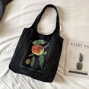 Détail d'un sac à bandoulière en toile noire avec motif pêche et texte sur draps