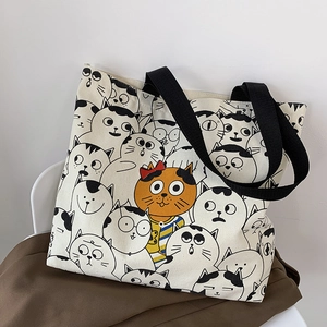 Close-up of cream canvas tote bag with cute cartoon cat prints and black handles