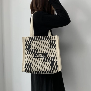 Detail of large canvas tote bag featuring bold black geometric stripes and ABLE text