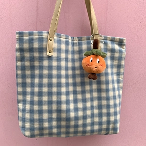 Blue plaid canvas tote bag with a cute plush orange fruit pendant hanging on it