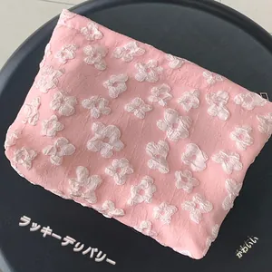 Macro shot of pink textured fabric makeup bag with 3D floral pleated pattern details