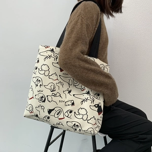 Detailed view of large canvas tote bag featuring whimsical dog illustrations on a model