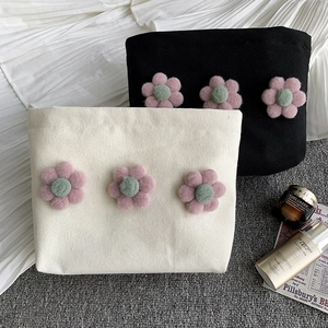 Detail of canvas makeup bag with three plush 3D flower decorations and zipper closure