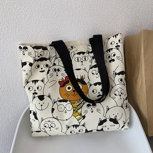 Detail of canvas tote bag featuring cute cartoon cat prints and durable black handles