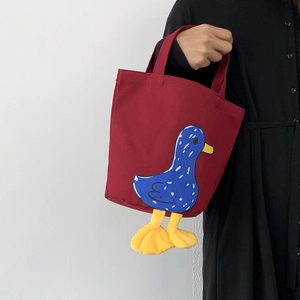 Detail view of red canvas lunch bag featuring a cute 3D cartoon duck design with yellow feet