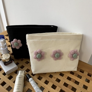 Close-up of canvas makeup bag featuring 3D felt flowers and top zipper closure
