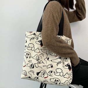 Detail of canvas tote bag featuring minimalist cartoon dog illustrations and black straps