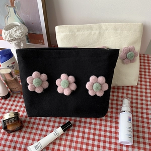Detail of canvas cosmetic bags with 3D floral accents and metal zipper closure