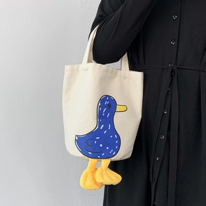 Detail of canvas tote bag featuring blue cartoon duck print and 3D plush feet