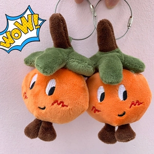 Detail of two plush persimmon charms with green leaves and steel ring keychains