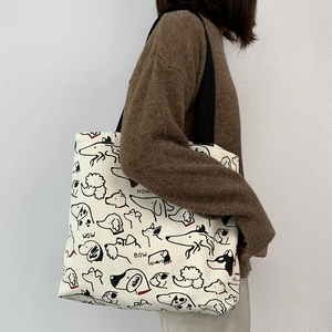 Detail of canvas tote bag featuring whimsical black dog illustrations and wide black straps