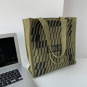 Detail view of army green canvas tote bag with black geometric stripes and wide strap