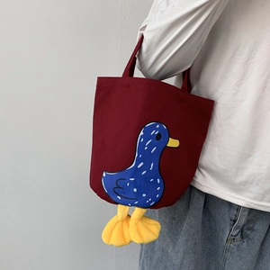 Detail of red canvas lunch bag with cartoon duck print and 3D plush feet accents
