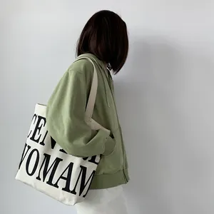 Detail of large canvas tote bag with black lettering paired with green hoodie