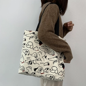 Detailed shot of large canvas tote bag with artistic puppy sketches and black straps